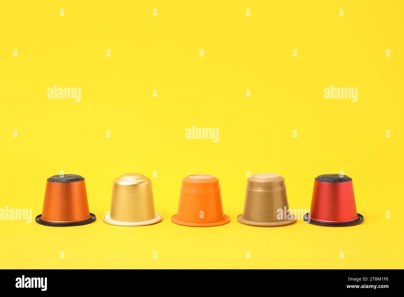 Many plastic coffee capsules on yellow background Stock Photo