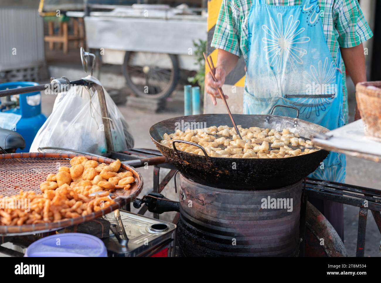 Deep frying long dough stick, chinese style doughnut type or churros in giant pan with hot oil. Stock Photo