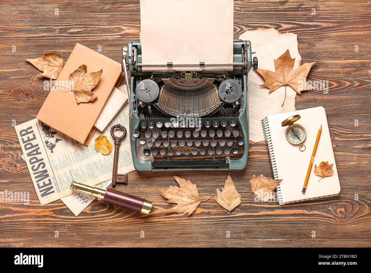 Vintage typewriter, compass, spyglass, book, notebook, newspaper and autumn leaves on wooden background Stock Photo