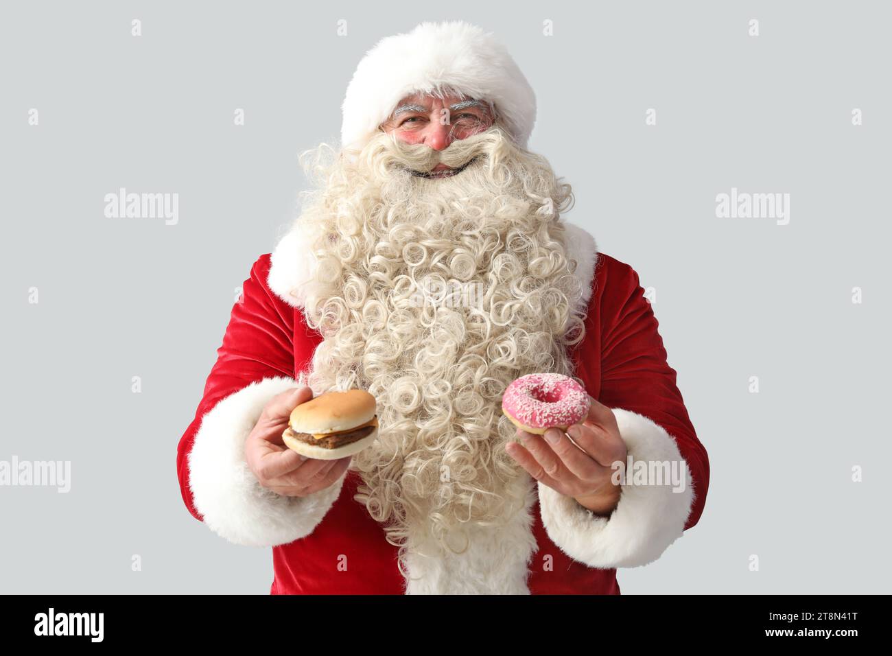 Santa Claus with tasty donut and burger on white background Stock Photo