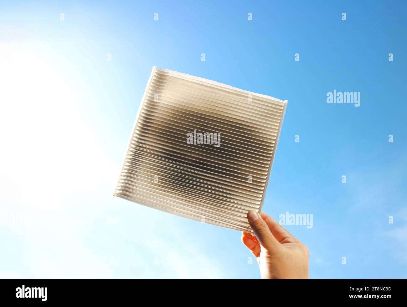 Car air conditioner filter clogged and dirty in a hand on blue sky