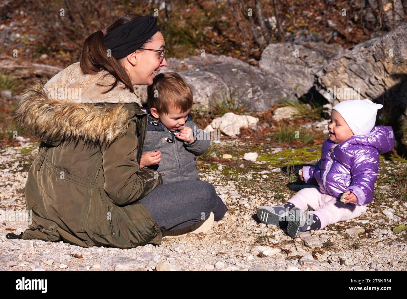 Mother with toddler and baby girl sitting on the ground in nature Stock ...