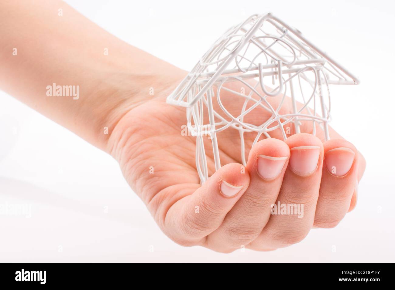 Little model house made of white metal wire in hand Stock Photo