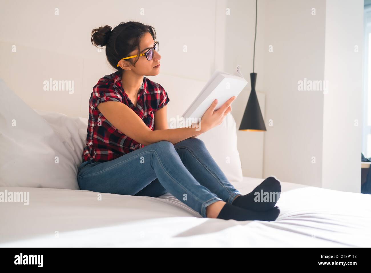 Side view of a young woman sitting comfortable reading a book in an