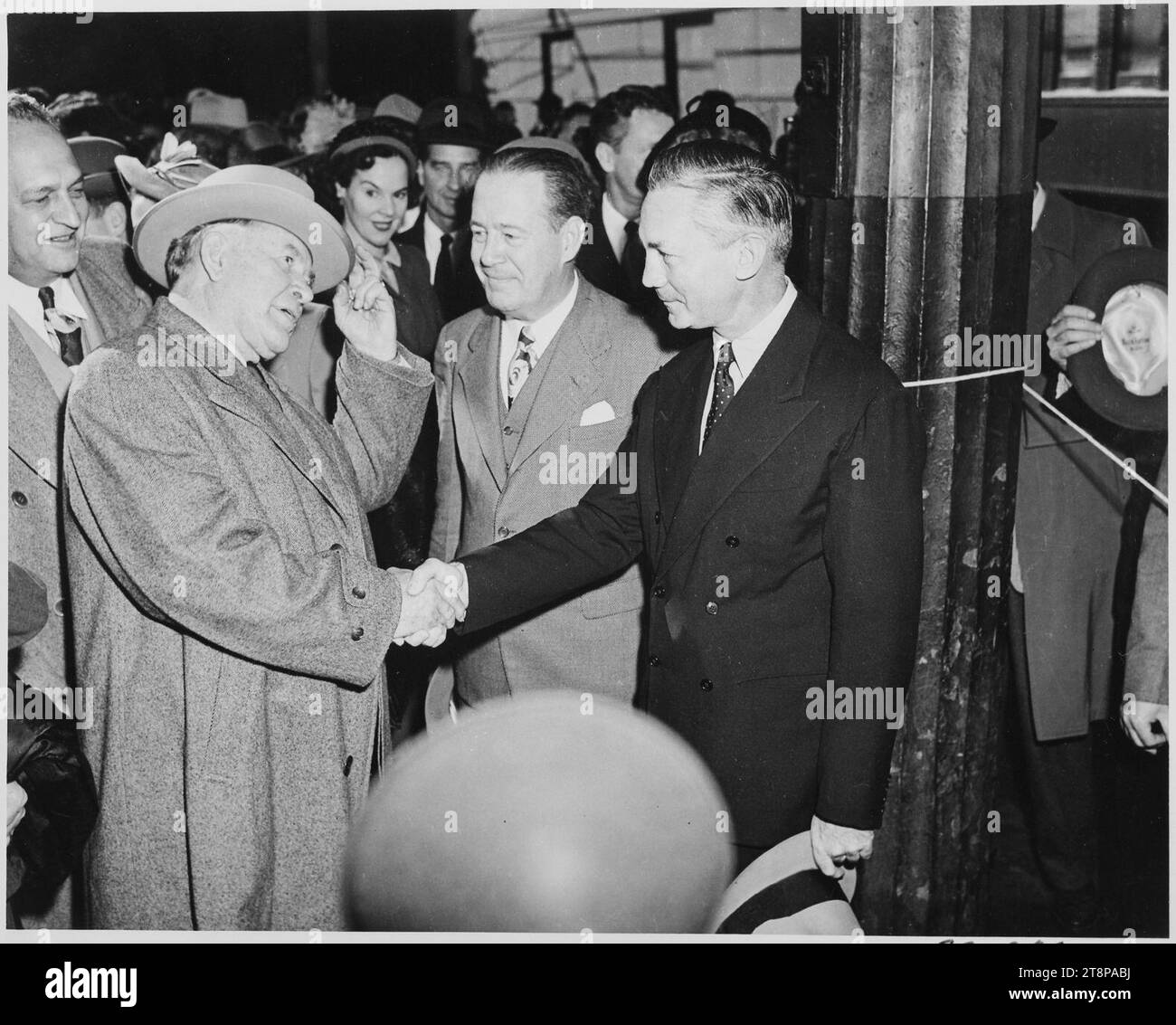 Vice President-elect Alben W. Barkley shakes hands with James V. Forrestal, with others looking on. - Stock Photo