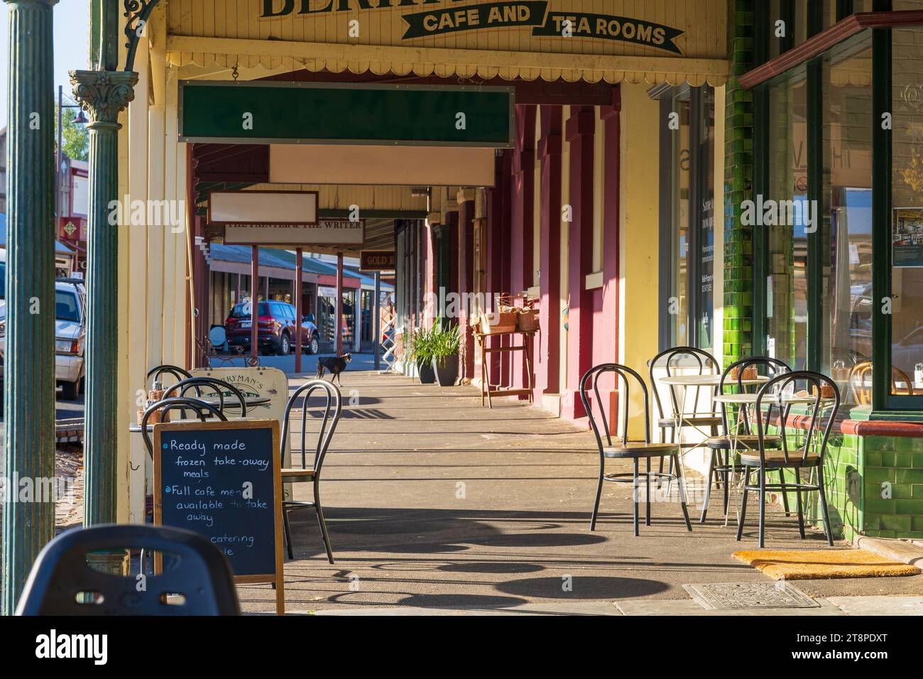 Café tables and chairs under the verandas of an historic streetscape in late afternoon light at Maldon in Central Victoria, Australia. Stock Photo