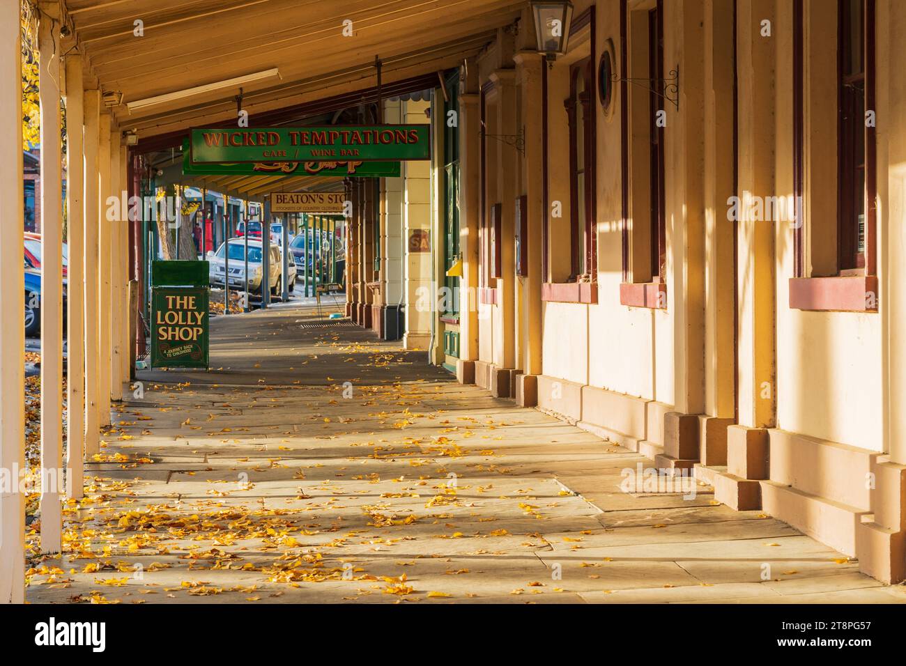 Autumn leaves scattered under the verandas of an historic streetscape in late afternoon light at Maldon in Central Victoria, Australia. Stock Photo