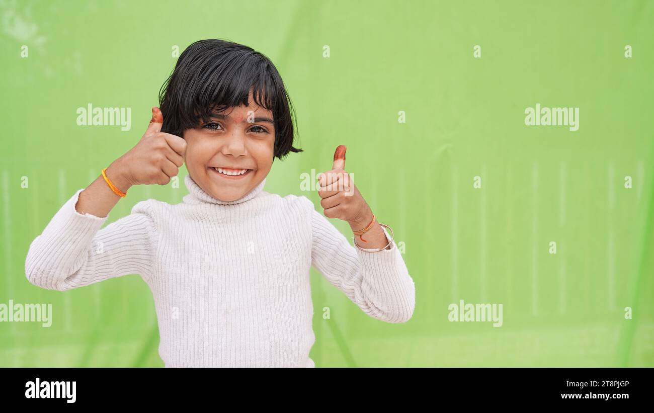 Happy positive little girl in white turtleneck showing thumb up like