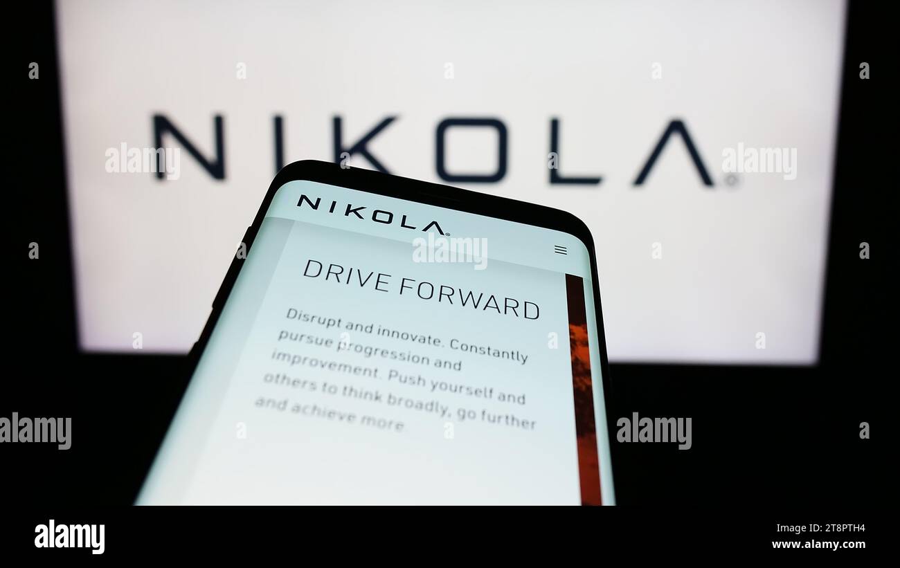 Smartphone with website of US electric vehicle company Nikola Corporation in front of business logo. Focus on top-left of phone display. Stock Photo