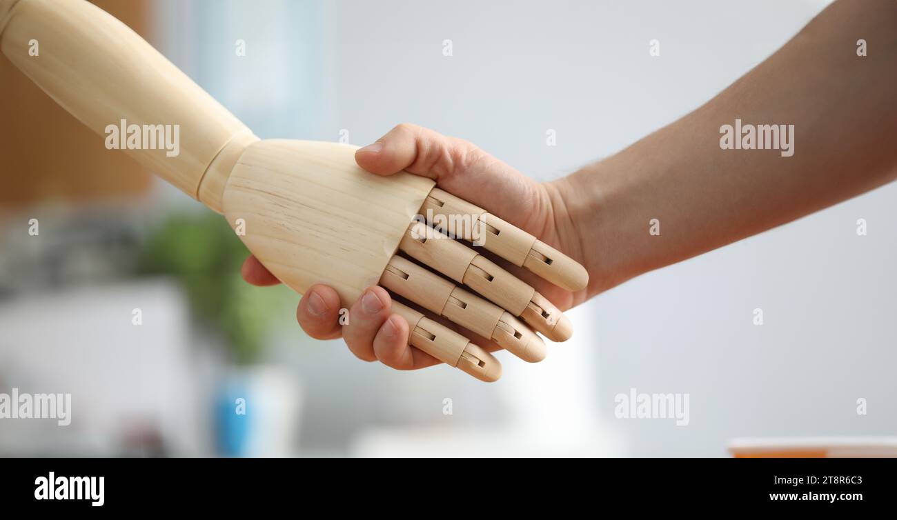 Closeup view of person shaking wooden prosthesis hand. Handshake of