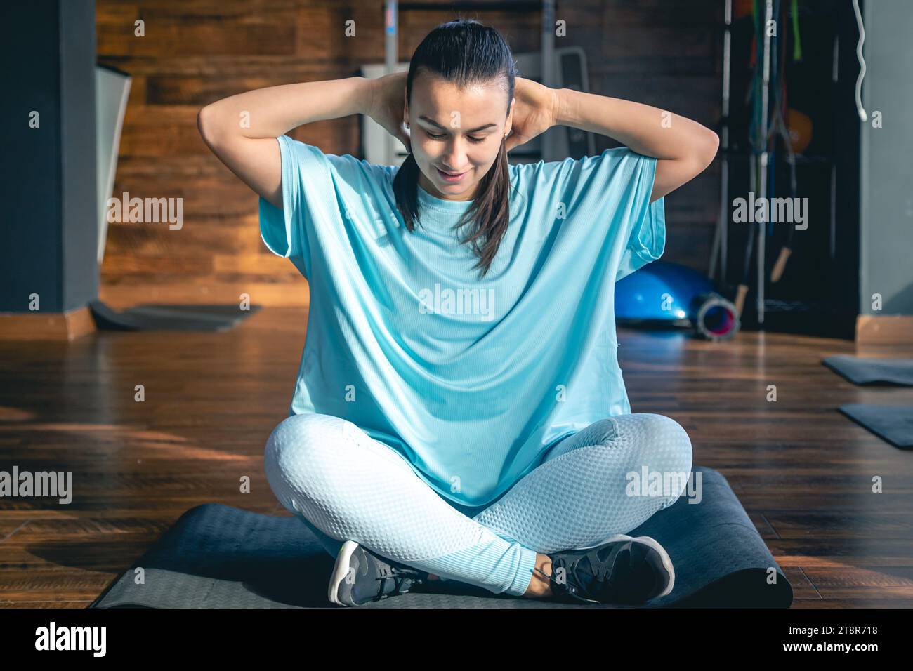 Young woman sitting on a mat in a fitness center, doing yoga and ...