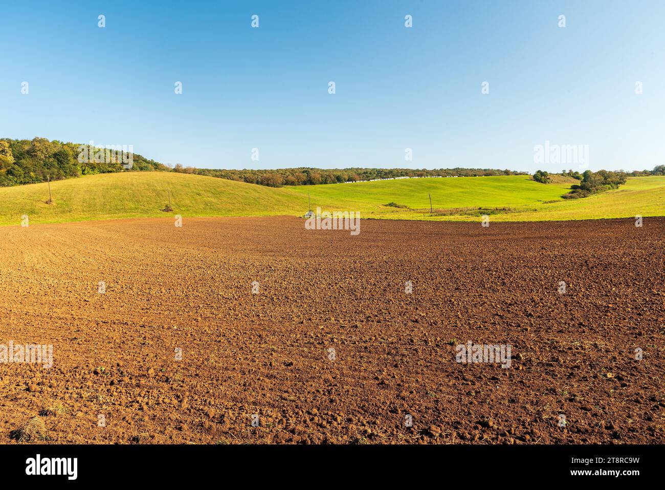Autumn rolling landscape with field, meadows, colorful forest and clear sky near Silica village in Slovensky kras in Slovakia Stock Photo