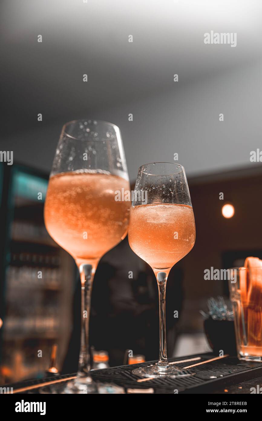Glass of ice cold Aperol spritz cocktail served in a wine glass, placed on a bar counter Stock Photo