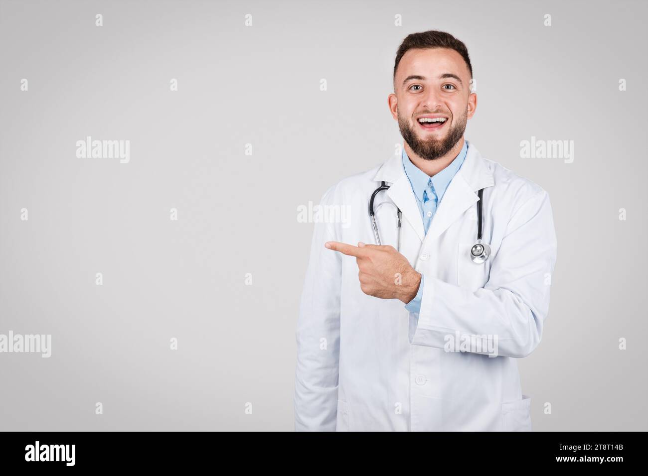 Joyful young male doctor pointing to the side at free space Stock Photo