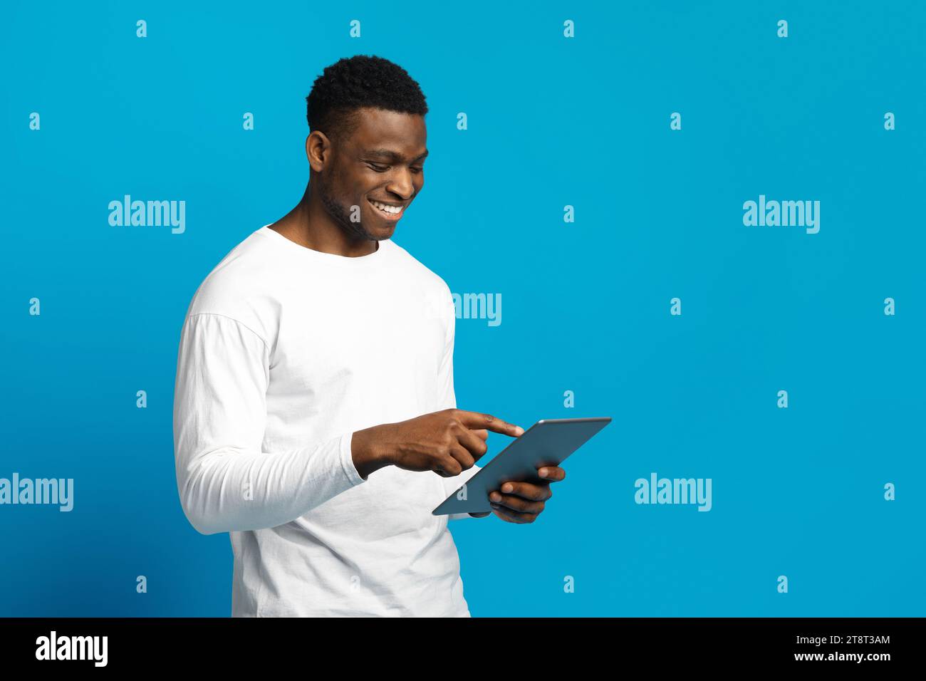 Happy young black guy using digital tablet Stock Photo