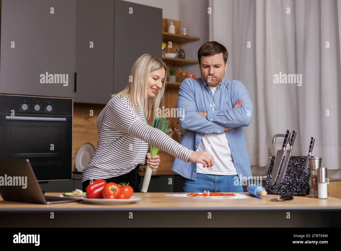 Leave Me Alone. A woman is preparing food, and a man is talking to her, and is not satisfied with the way she is cooking Stock Photo