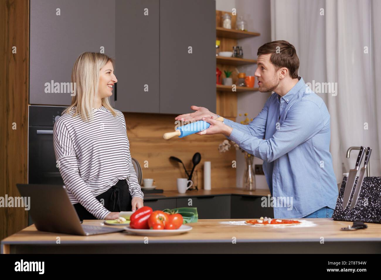 Leave Me Alone. A woman is preparing food, and a man is talking to her, and is not satisfied with the way she is cooking Stock Photo