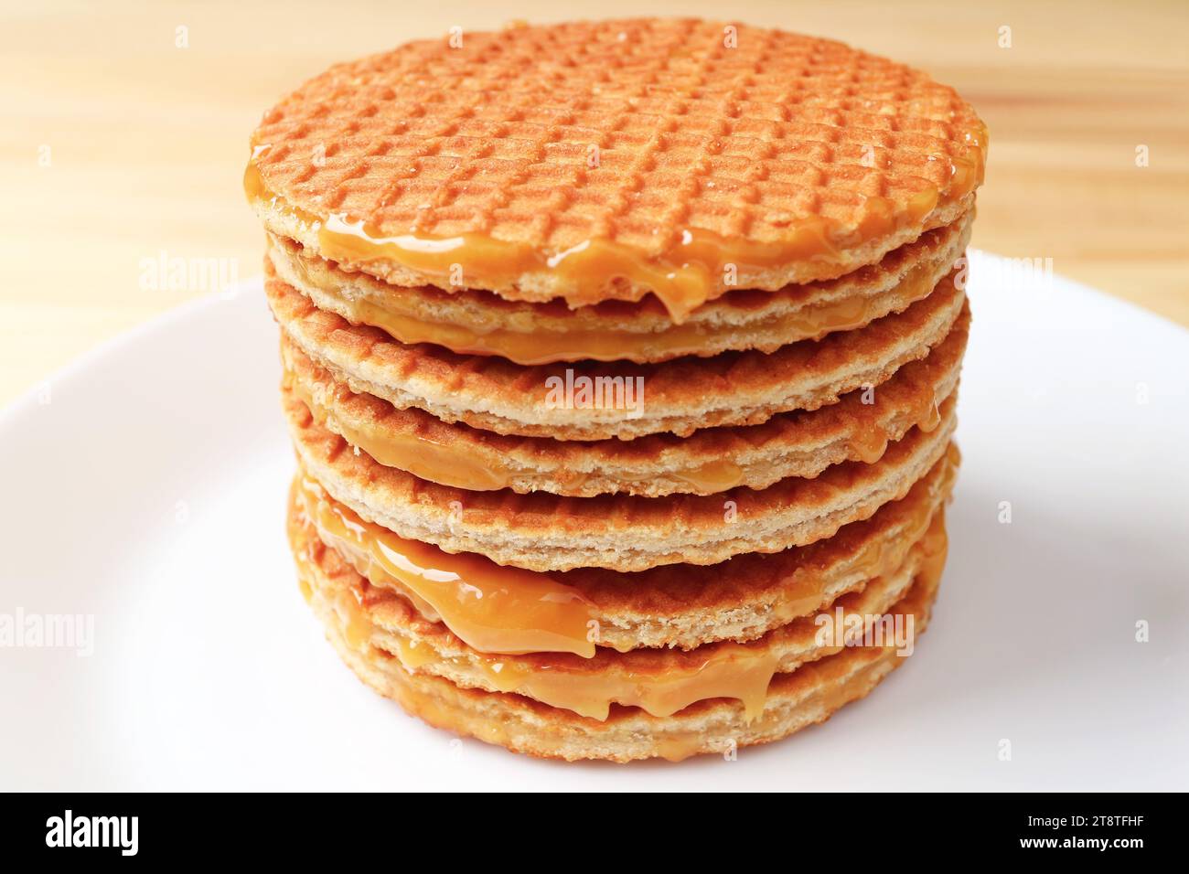 Stack of Mouthwatering Stroopwafels on the White Plate Served on Wooden Table Stock Photo