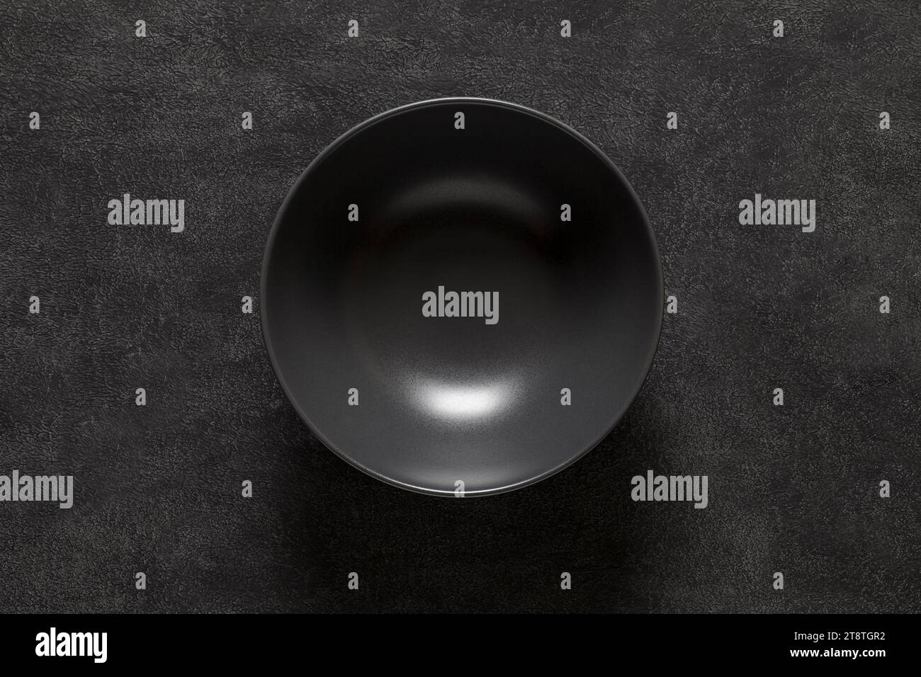 Bowl black empty deep, on dark background, top view, space to copy text. Stock Photo