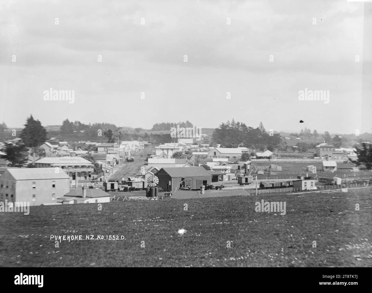 General view of Pukekohe, View of Pukekohe looking across a grassy area towards the railway station and business premises in the middle distance. The Pukekohe Hotel (with name on the roof) is on the left opposite the railway yard. Photograph taken ca 1910 Stock Photo