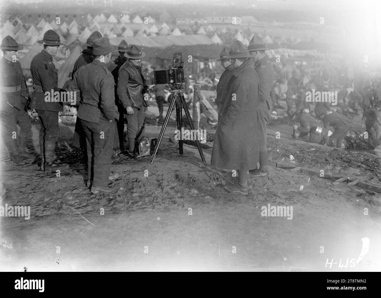 New Zealand soldiers looking at the official photographer's camera in France, World War I, NZ soldiers inspect the official photographer's cine camera mounted on a tripod in the grounds of the New Zealand Infantry Base Depot at Etaples. Tents and huts can be seen in the background. Photograph taken 15 January 1918 Stock Photo