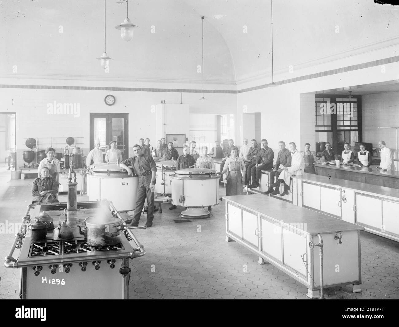 The German kitchen at the dye works used by New Zealand Divisional Headquarters, Leverkusen, Germany, Interior view of the German kitchen in the dye works at Leverkusen, Germany, used by the New Zealand Divisional Headquarters during the allied occupation after World War I. Shows a number of civilians in the vast kitchen who pose for the camera. Photograph taken March 1919 Stock Photo