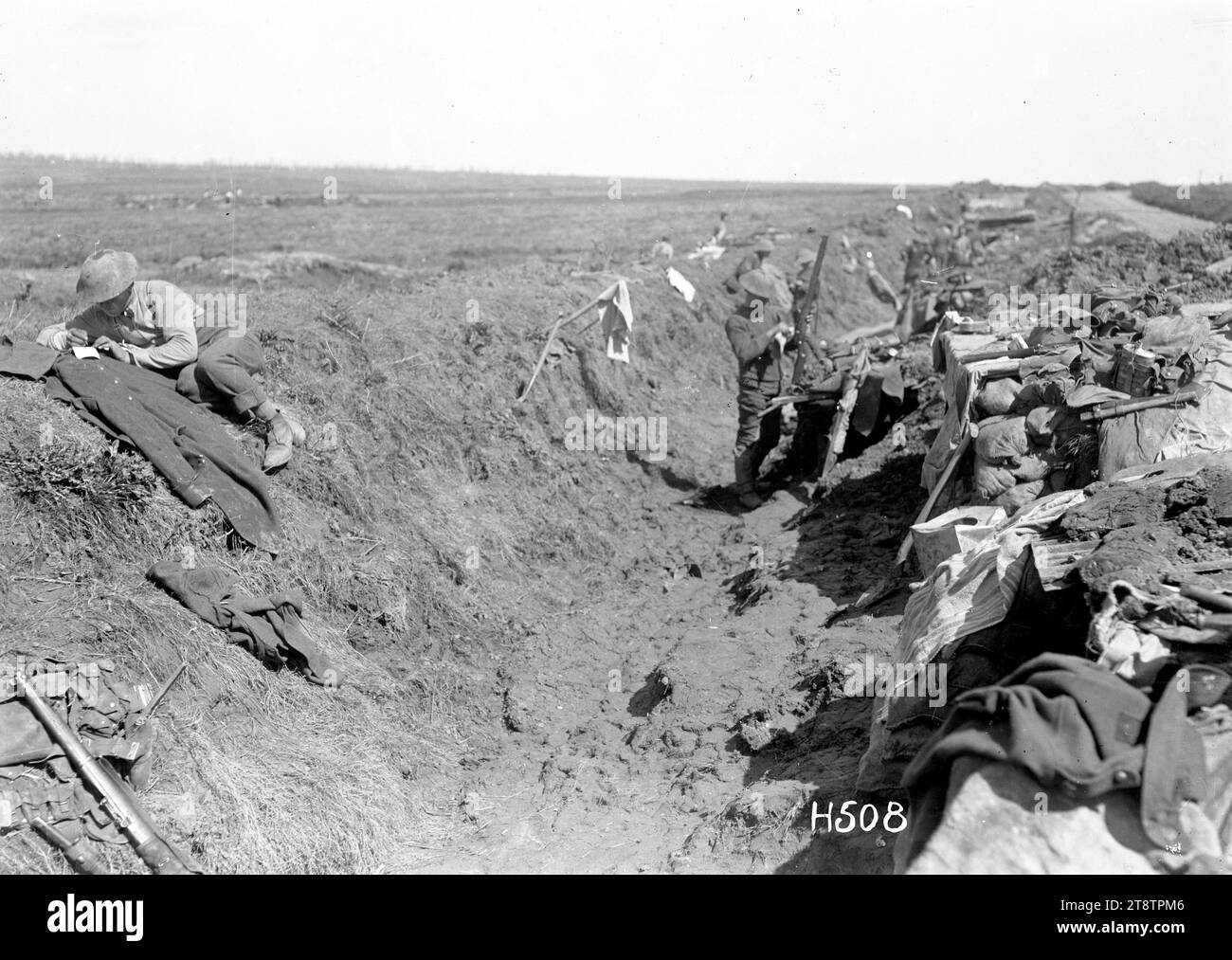 New Zealand troops in the support line at the Western Front, New Zealand soldiers shown in the support line waiting to go up to the front line. Some sleep in funk holes while one soldier cleans his rifle. Another lies on a bank above the trench. Photograph taken Colincamps 15 April 1918 Armytage Sanders Stock Photo