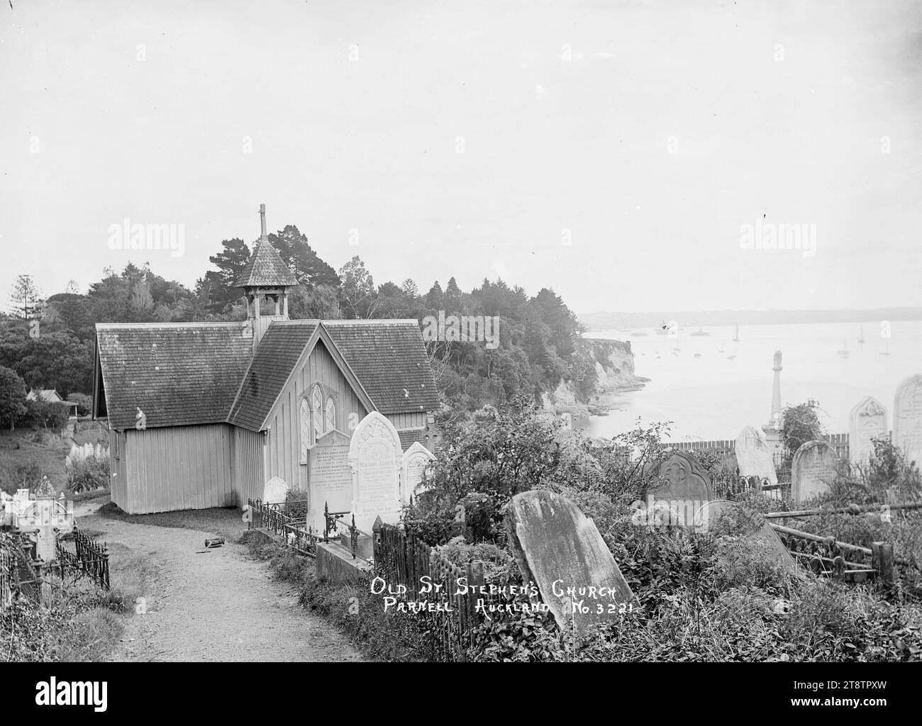 St Stephen's Church and burial ground, Judges Bay, Parnell, View of St Stephen's Church looking north west over Judges Bay towards the city in the distance. In the foreground is the graveyard. Headstones belonging to members of the Morton, Hanly and Corbett families are identifiable from the inscriptions ca 1910 Stock Photo