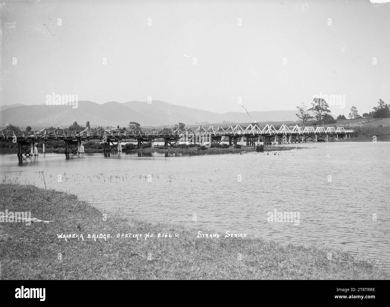 View of the bridge across the Waioeka River, Opotiki, View of Waioeka River and bridge with hills in the far distance. in early 1900s Stock Photo