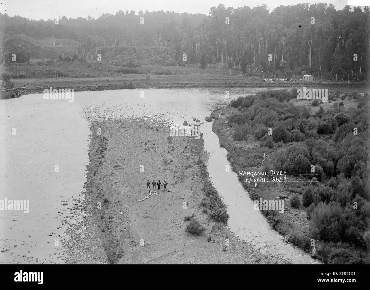 Wanganui, New Zealand River at Kakahi, Wanganui, New Zealand River at Kakahi, circa 1908, with a stand of native bush in the background, and four men standing on a piece of land which has the main river on the left and a narrow channel of the river on the right Stock Photo