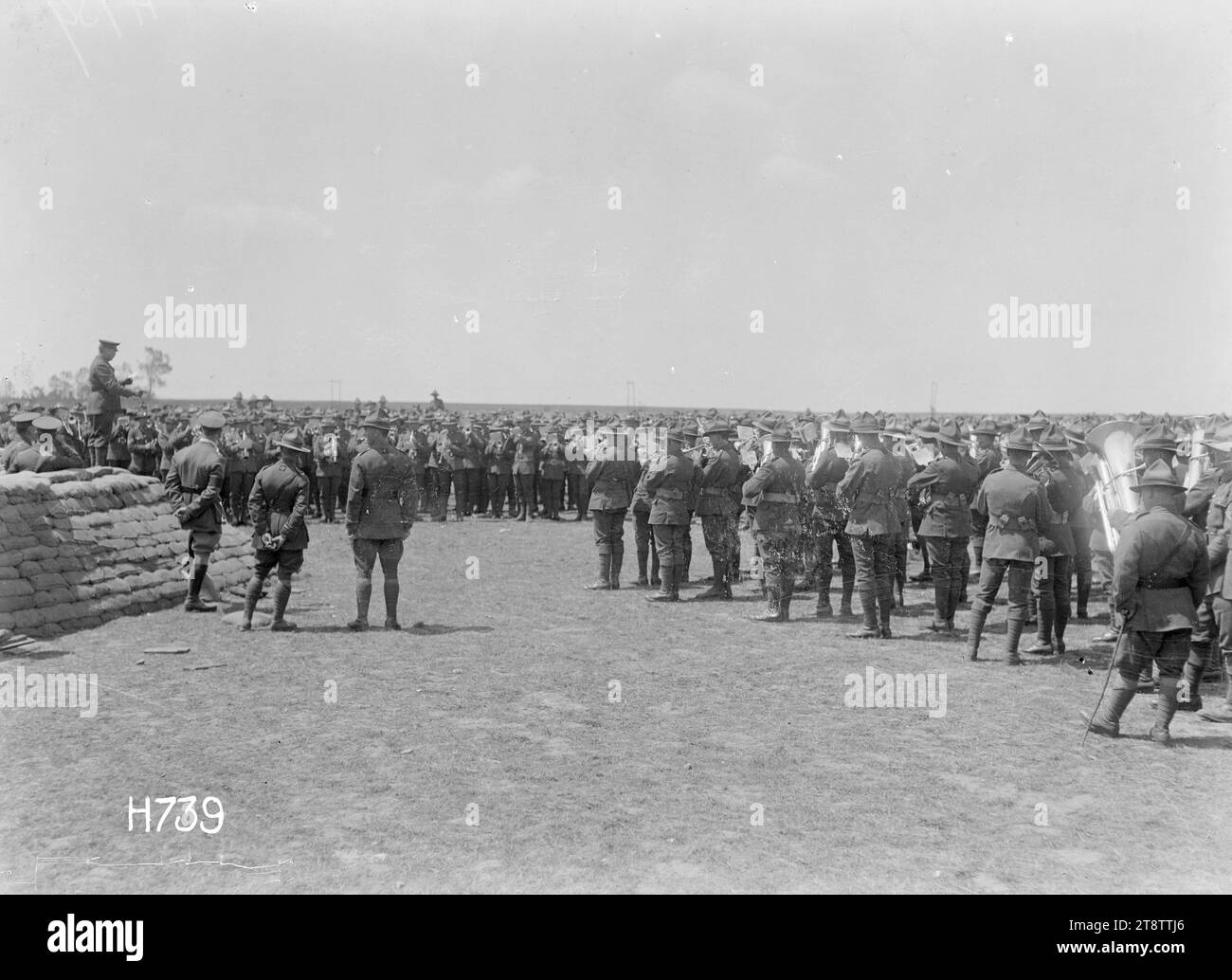 The massed bands playing at the New Zealand Divisional Band Contest, France, A general view looking towards the massed military bands playing at the New Zealand Divisional Band Contest under the conductorship of the judge who stands on a wall of sandbags, far left. A Canterbury Regiment won the contest. Photograph taken Authie 27 July 1918 Stock Photo