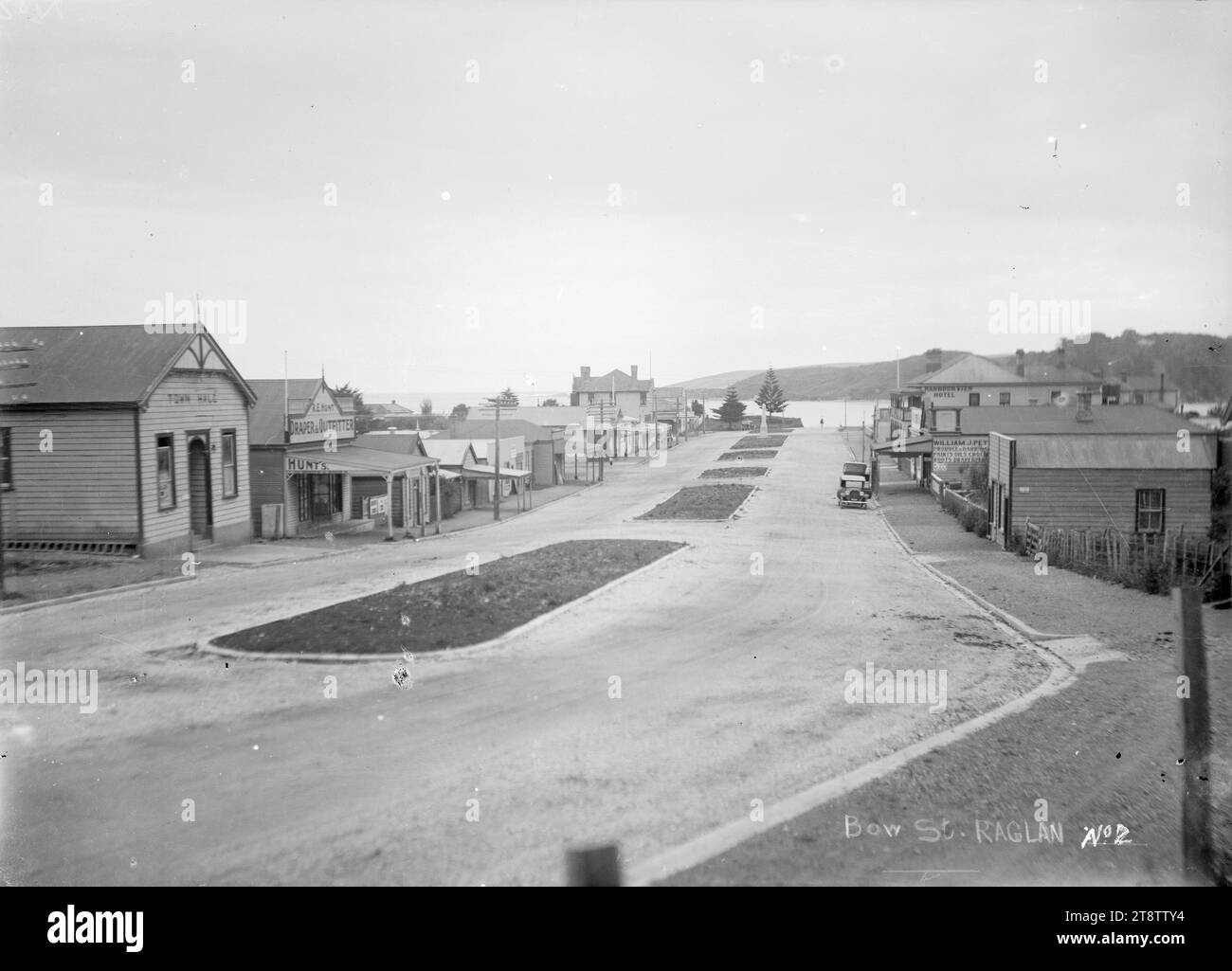 Bow Street, Raglan, New Zealand, circa 1920s, Bow Street, Raglan, New Zealand. Taken circa 1920s. The Raglan, New Zealand Town hall is on the left, with the premises of R E Hunt, Draper & Outfitter, next door. On the right the Harbour View Hotel is visible with the premises of William J Petchell partially visible Stock Photo