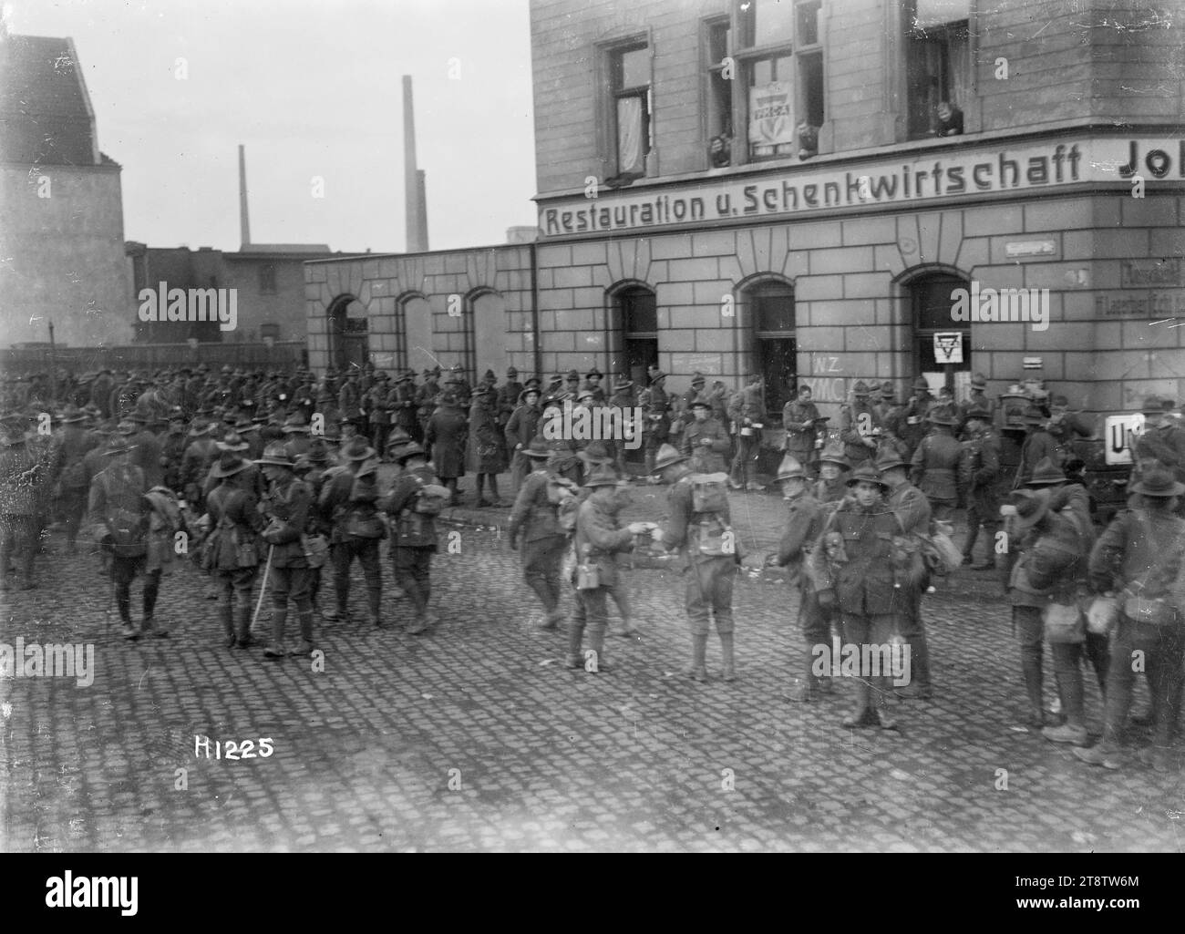 World War I New Zealand troops outside the YMCA in Ehrenfeld, Cologne, A large group of New Zealand soldiers shown mingling on the cobblestones outside the NZ YMCA in Ehrenfeld, a suburb of Cologne in Germany. YMCA notices appear on the window of a building with the German words 'Restauration u. Schenkwirtschaft' on it. 'NZ YMCA' is also written on the wall. Photograph taken after the end of World War I, probably December 1918 Stock Photo
