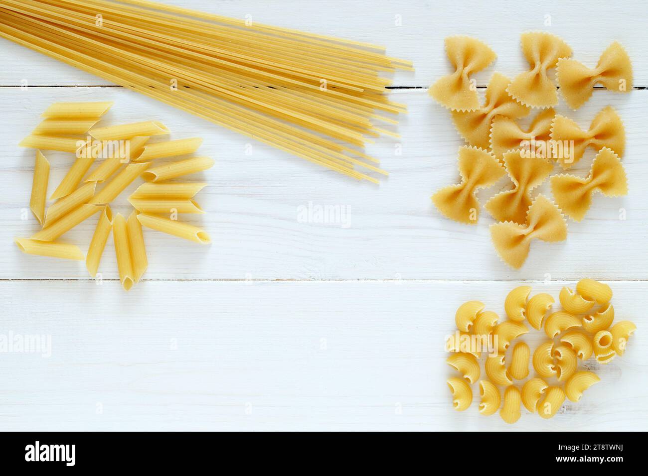 Maccheroni raw, mixed, on white wooden board background, top view, space to copy text. Stock Photo