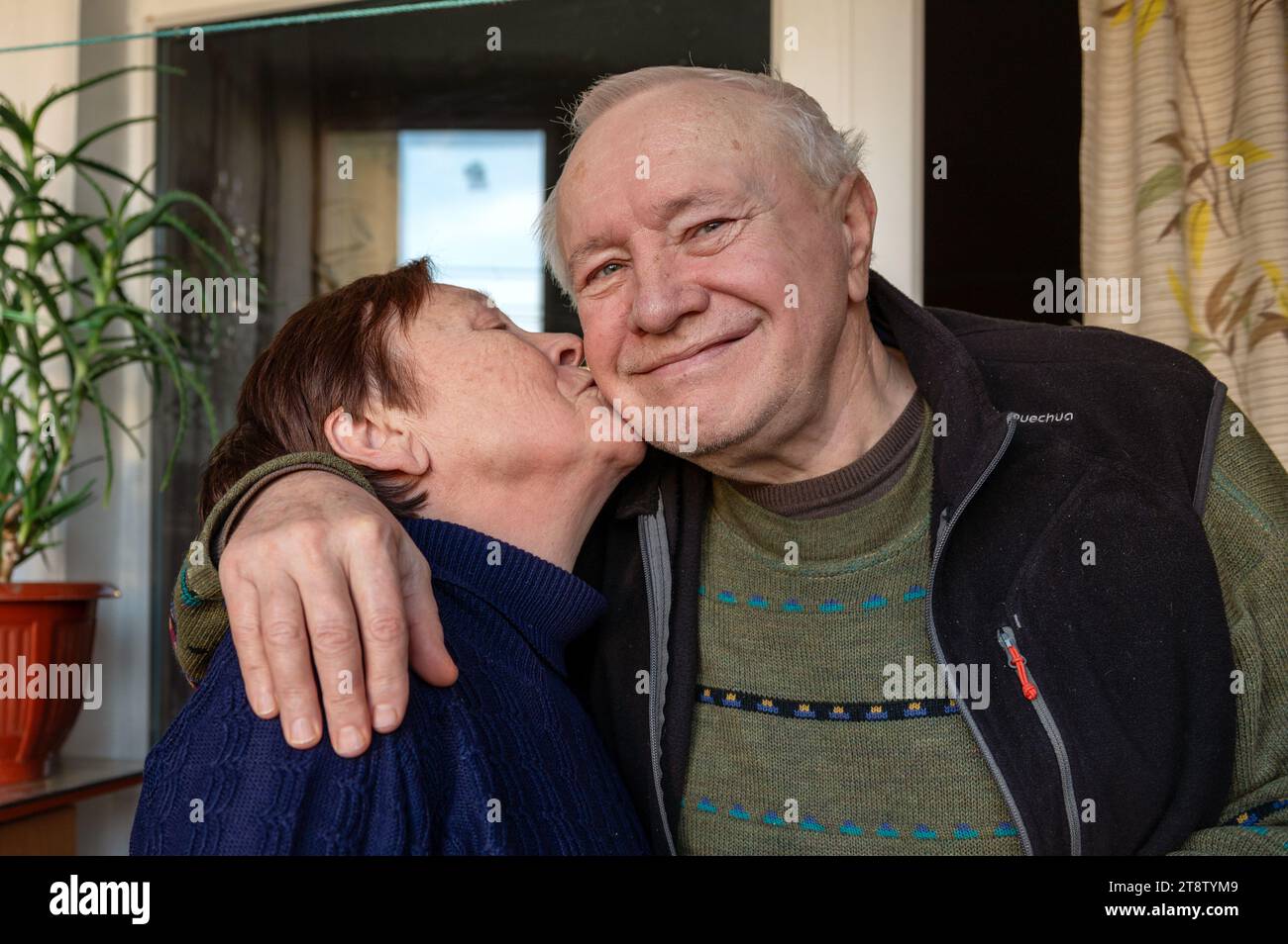 Nice aged woman kissing her beloved husband. Elderly woman lovingly kisses her husband on the cheek Stock Photo
