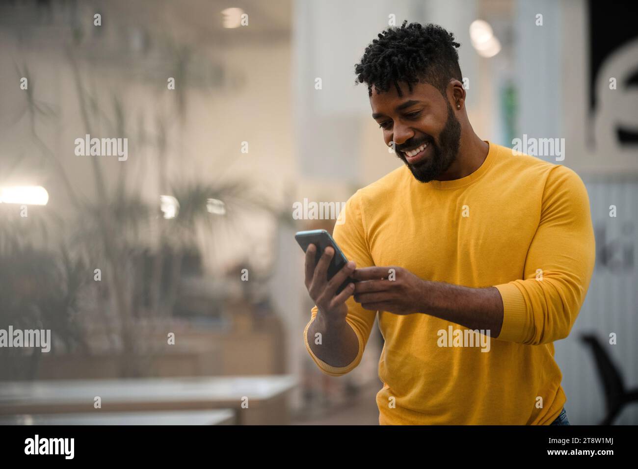 African American man using smart phone while leaning on table Stock Photo