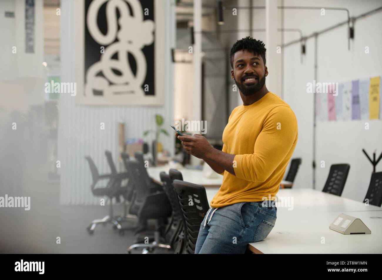 African American man using smart phone while leaning on table Stock Photo