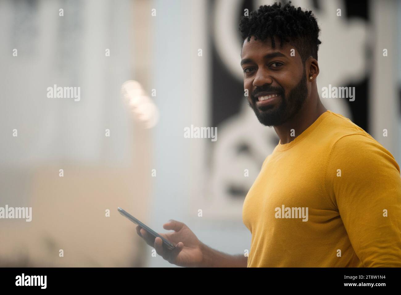 African American man looking at the camera while holding smart phone Stock Photo