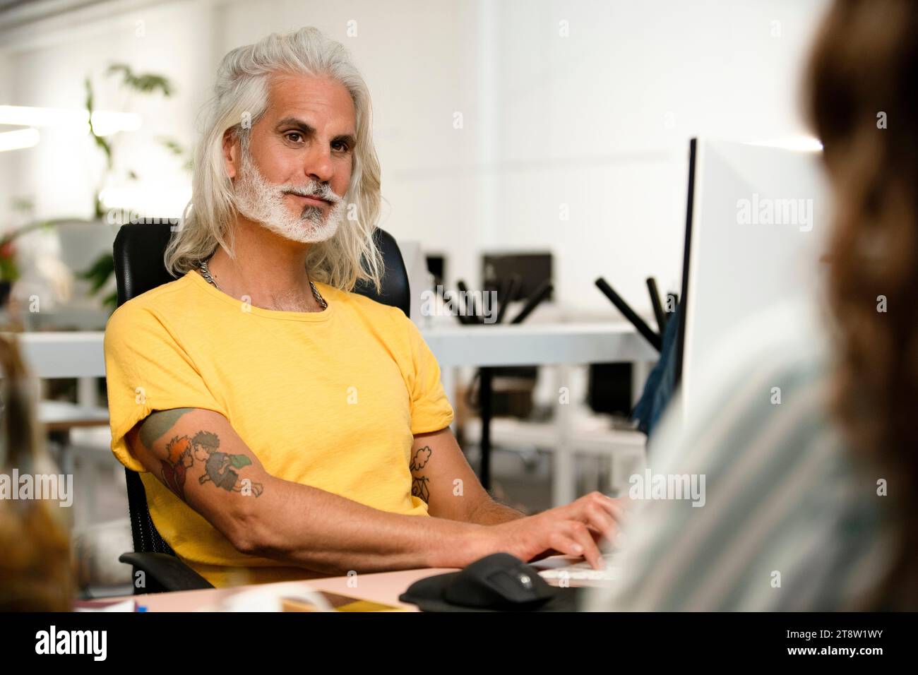 Computer programmer using computer while listening to coworkers Stock Photo