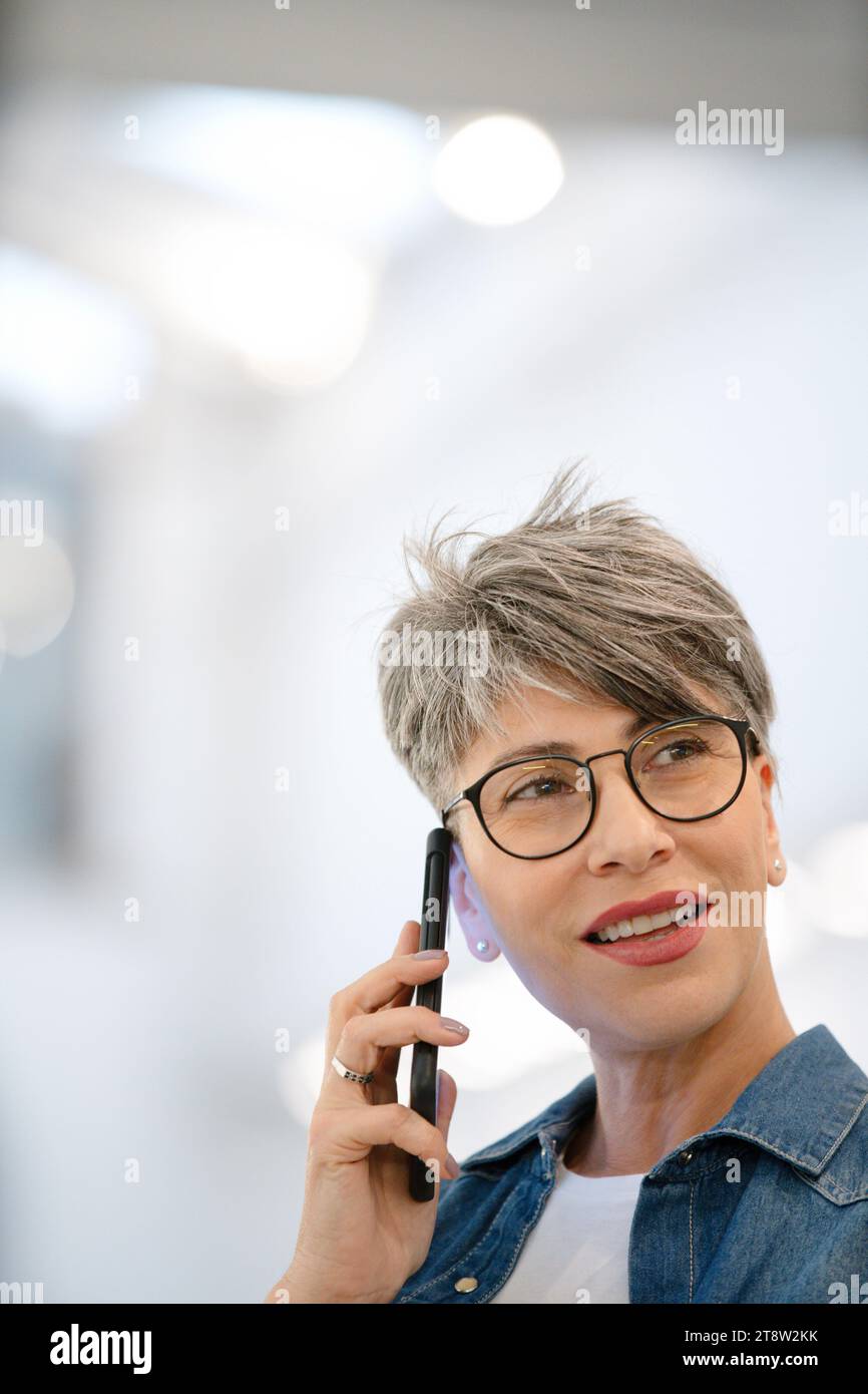 Female entrepreneur listening voice mail on smart phone Stock Photo