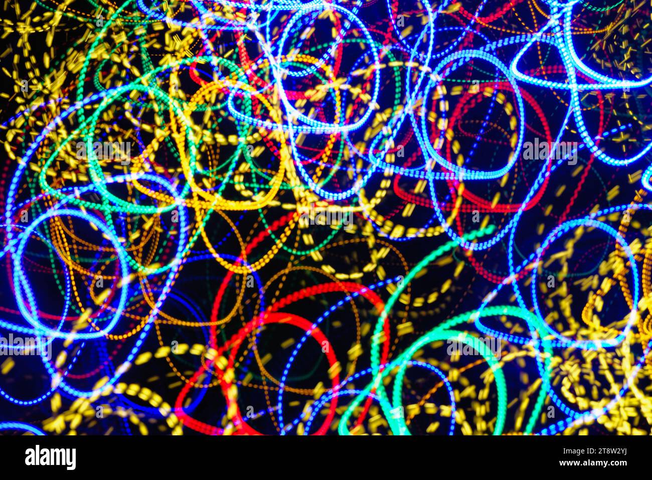 Blurred multi coloured light pattern streaks against a dark background creating abstract shapes Stock Photo
