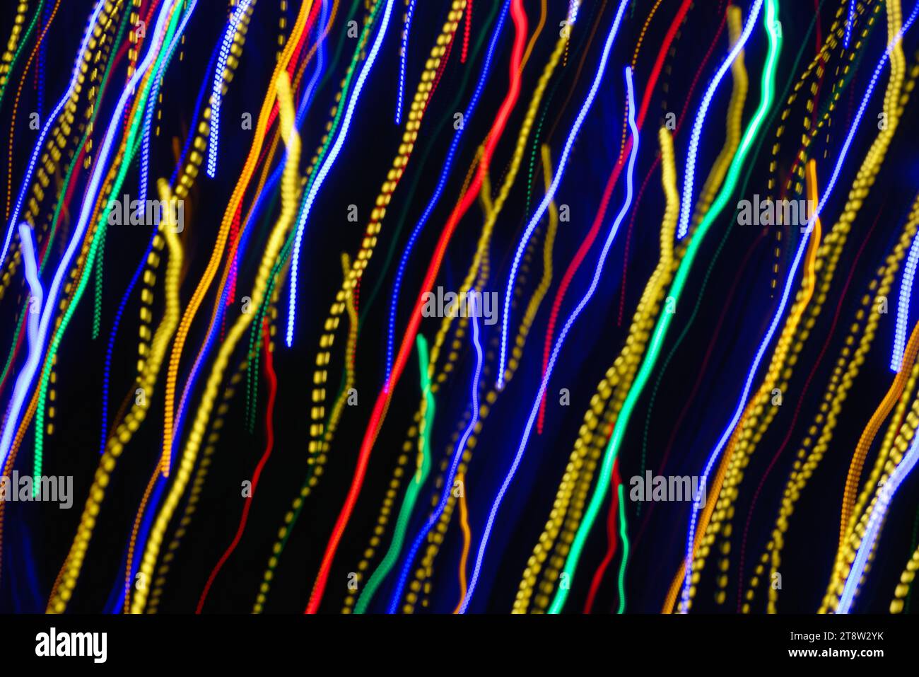 Blurred multi coloured light pattern streaks against a dark background creating abstract shapes Stock Photo