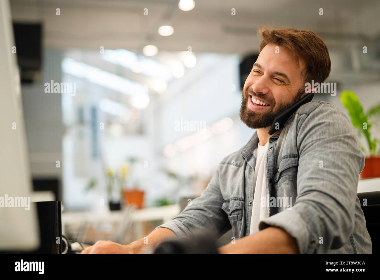 Male computer programmer talking on smart phone while working Stock Photo