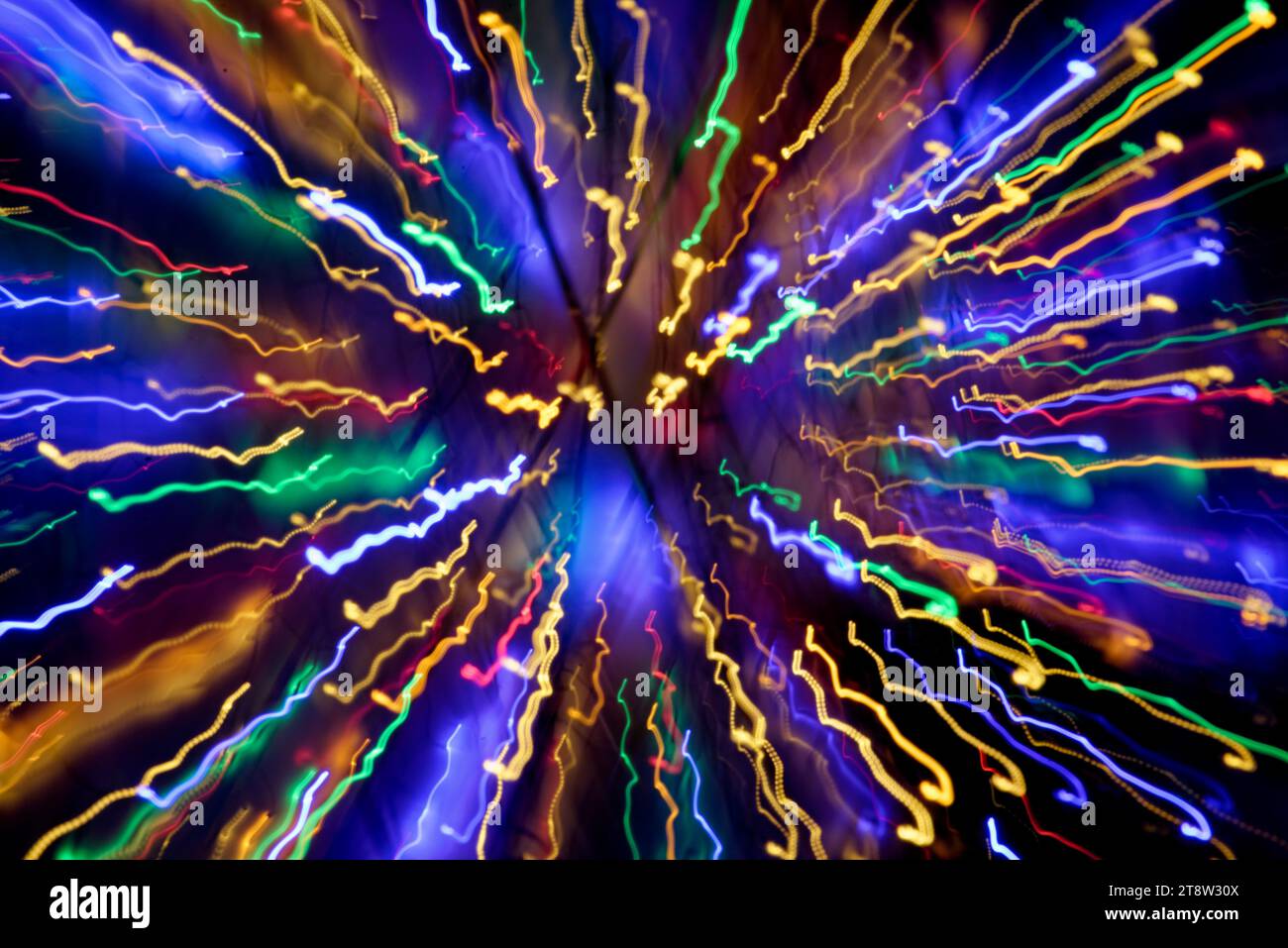 Blurred multi coloured light patterns streaks against a dark background creating abstract shapes Stock Photo