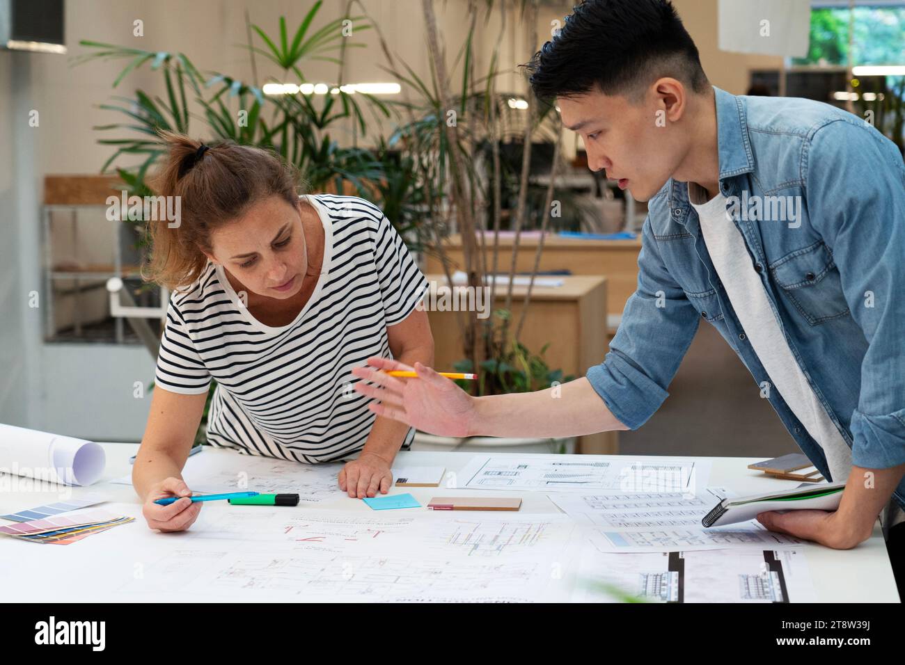 Architects discussing over blueprint while leaning on table Stock Photo