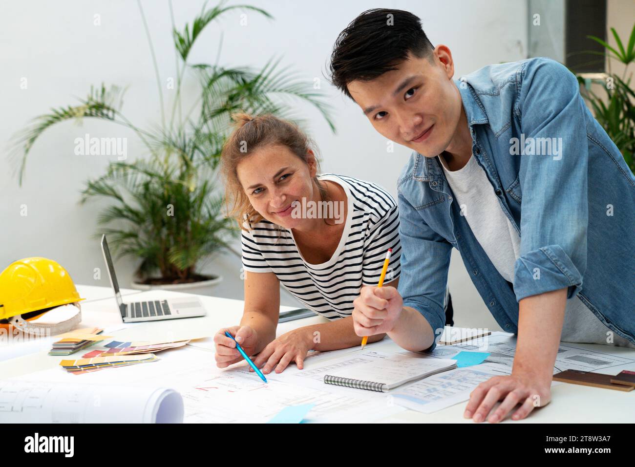 Two architects looking at the camera while leaning on table Stock Photo