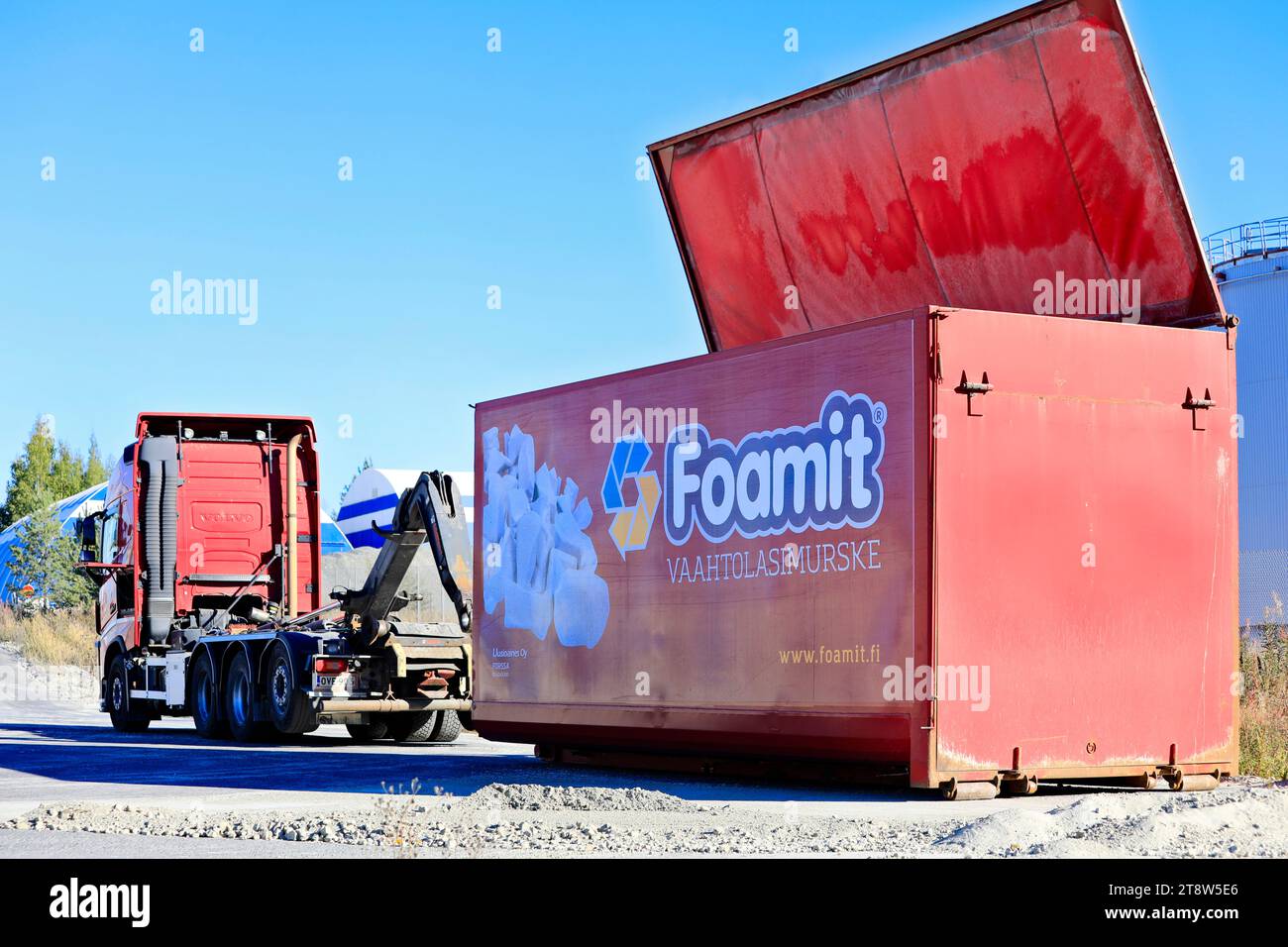 Red Volvo FH hooklift truck and detached Foamit foam glass transport trailer at Uusioaines Oy production plant. Forssa, Finland. September 9, 2022. Stock Photo