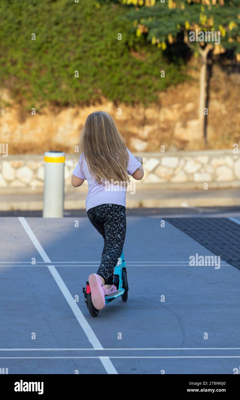 girl riding a scooter along a city street Stock Photo