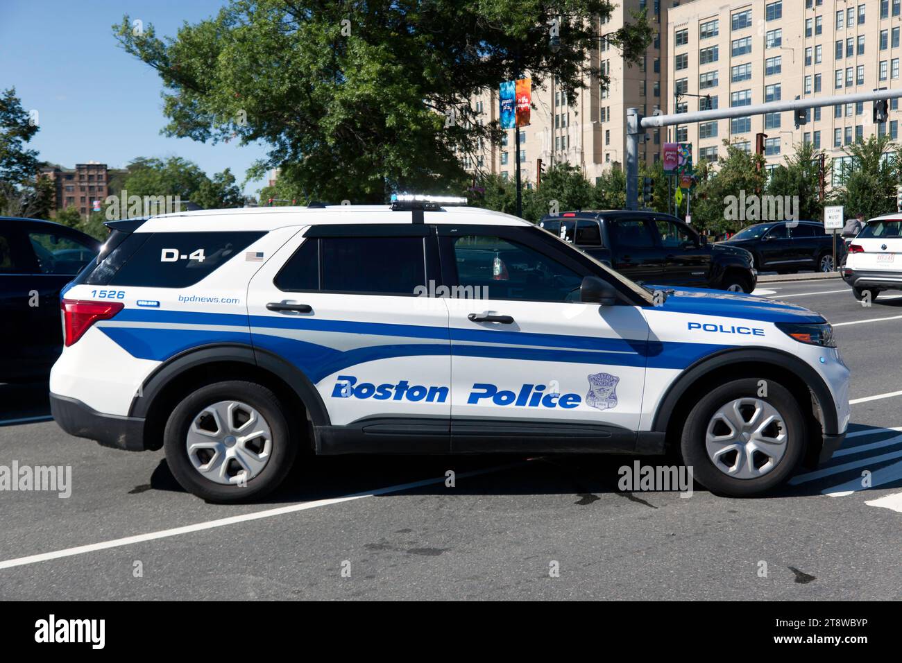 A police Officer using his vehicle to protect two workers working on utilities in the middle of the road at the junction of Park Drive and Boylston St Stock Photo