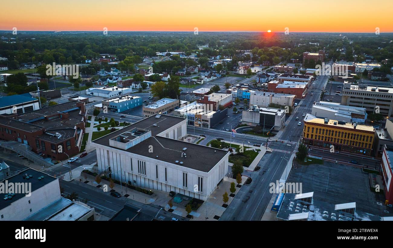 Red sun dawning over Muncie Indiana downtown buildings and courthouse at sunrise, aerial Stock Photo